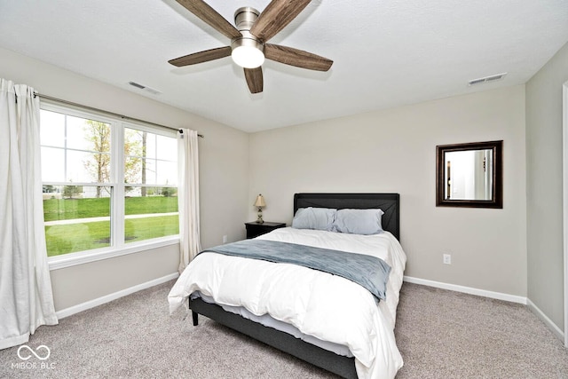 carpeted bedroom featuring baseboards, a ceiling fan, and visible vents