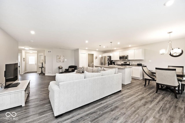 living area featuring recessed lighting, visible vents, dark wood finished floors, and a notable chandelier