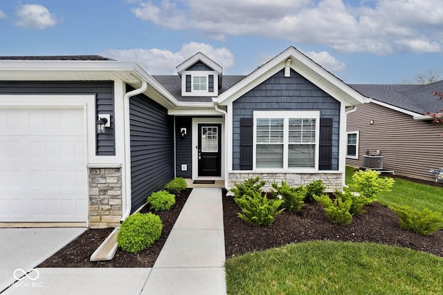 craftsman inspired home featuring roof with shingles, central AC unit, an attached garage, and stone siding
