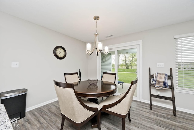 dining space with baseboards, a notable chandelier, wood finished floors, and visible vents
