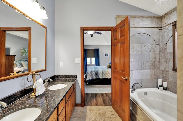bathroom with connected bathroom, ceiling fan, a sink, and a washtub