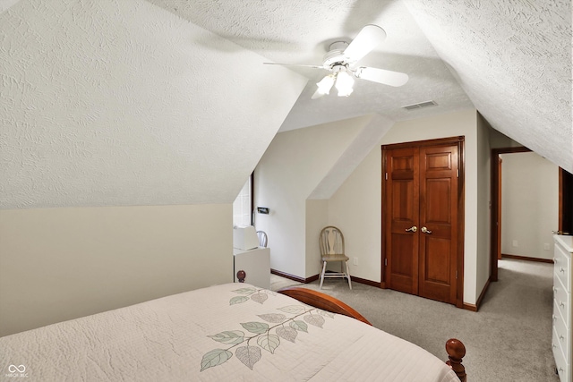 bedroom featuring lofted ceiling, a textured ceiling, visible vents, light carpet, and a ceiling fan