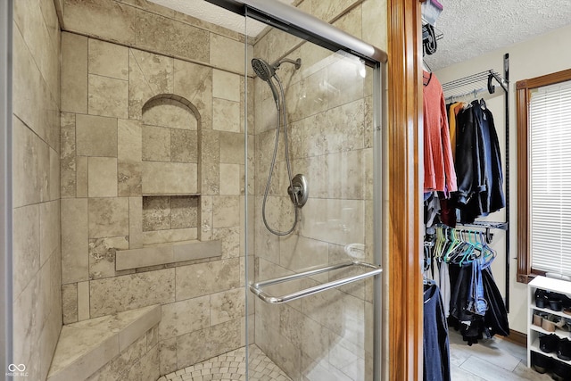 full bath featuring a stall shower, a spacious closet, and a textured ceiling