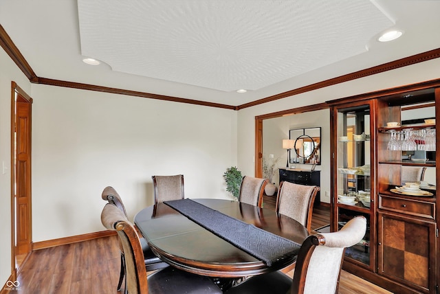 dining area featuring baseboards, crown molding, recessed lighting, and wood finished floors
