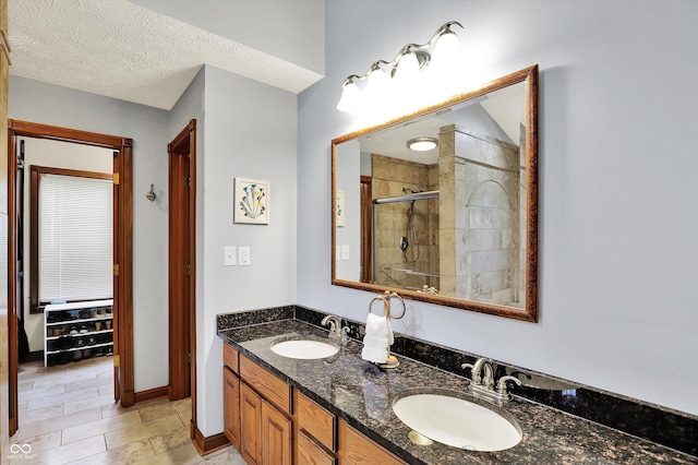 full bath with a sink, double vanity, baseboards, and a shower stall