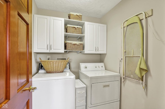 laundry area featuring a textured ceiling, washer and dryer, and cabinet space