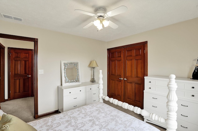 carpeted bedroom featuring a ceiling fan, a closet, a textured ceiling, visible vents, and baseboards