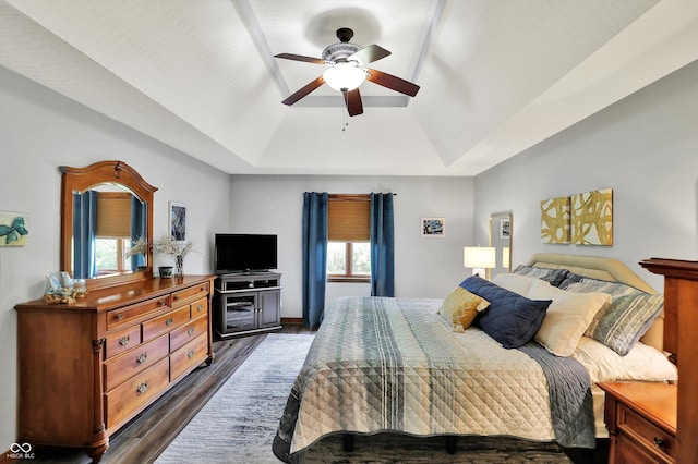 bedroom featuring dark wood-style flooring, a raised ceiling, and a ceiling fan