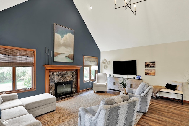 living room with wood finished floors, high vaulted ceiling, a fireplace, a notable chandelier, and baseboards