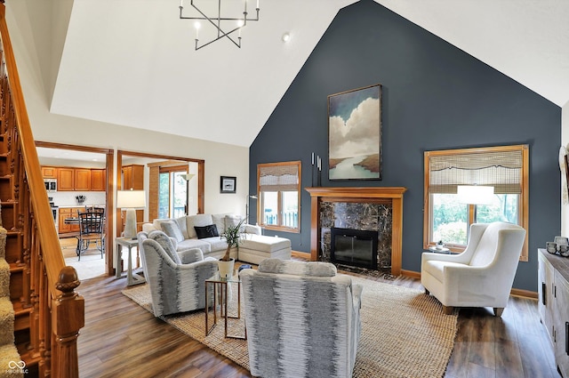 living area with a high end fireplace, an inviting chandelier, high vaulted ceiling, and wood finished floors