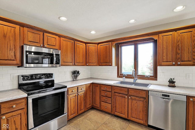 kitchen with a sink, brown cabinets, light countertops, and appliances with stainless steel finishes