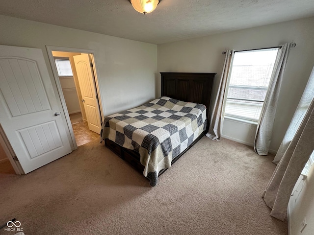 bedroom with a textured ceiling, light carpet, and baseboards