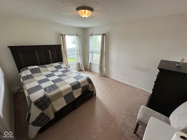 bedroom with a textured ceiling, light carpet, and baseboards