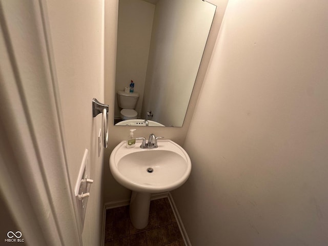 bathroom with toilet, a sink, and tile patterned flooring