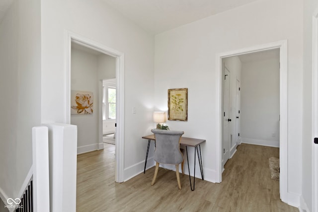 corridor with baseboards and light wood-style floors