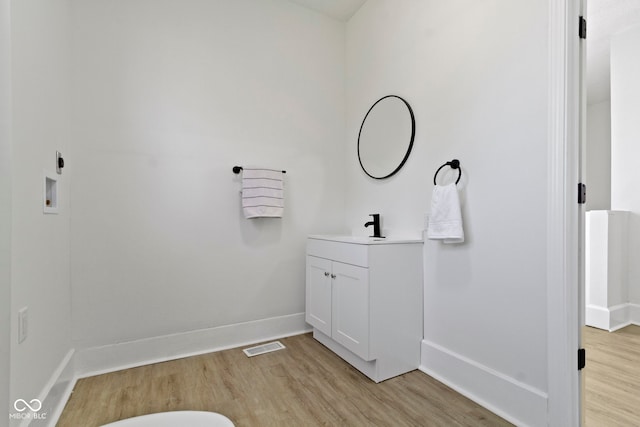 bathroom featuring vanity, baseboards, wood finished floors, and visible vents
