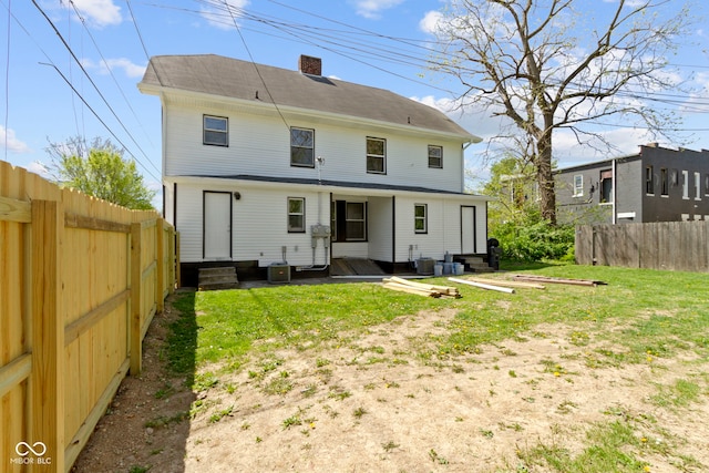 back of house featuring entry steps, a chimney, cooling unit, and a fenced backyard