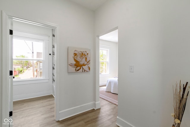 hall with baseboards and light wood-style flooring