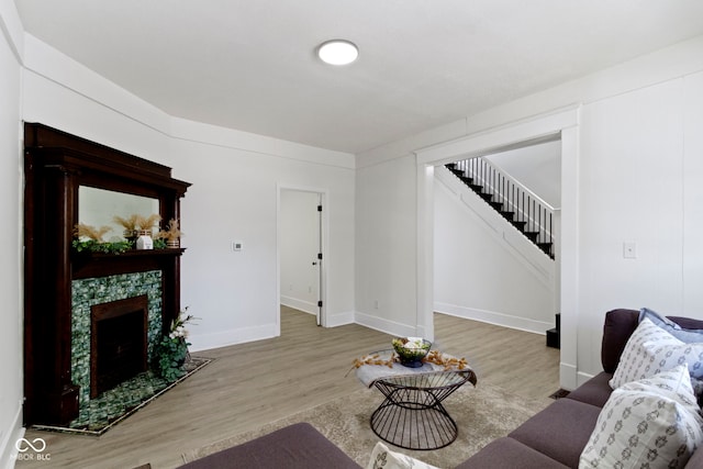 living room with stairs, baseboards, wood finished floors, and a fireplace