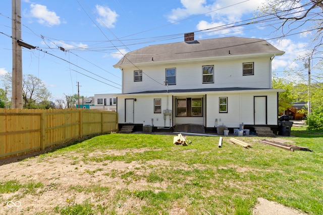 back of property with fence, cooling unit, a chimney, entry steps, and a yard