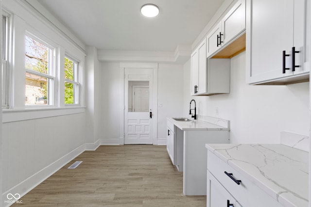 laundry room with baseboards, visible vents, a sink, and light wood finished floors