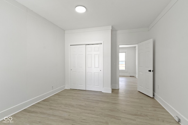 unfurnished bedroom featuring baseboards, a closet, and light wood finished floors