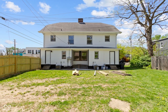 back of property featuring central AC, fence, a chimney, entry steps, and a lawn