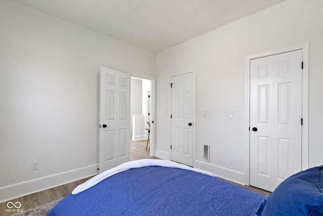 bedroom with baseboards, wood finished floors, and visible vents