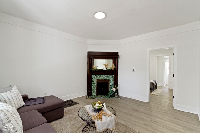 living room with light wood-style floors, baseboards, and a fireplace