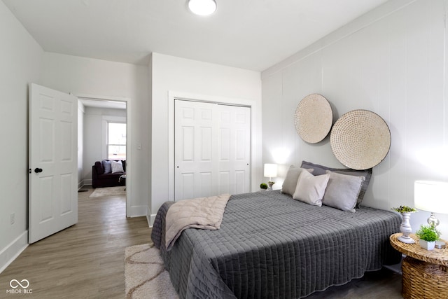 bedroom featuring baseboards, wood finished floors, and a closet