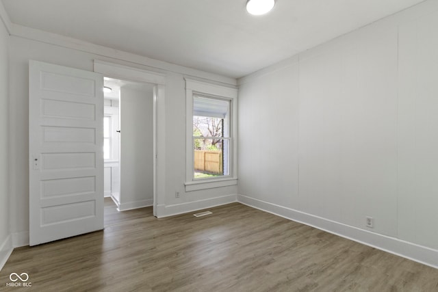 spare room with visible vents, baseboards, and wood finished floors