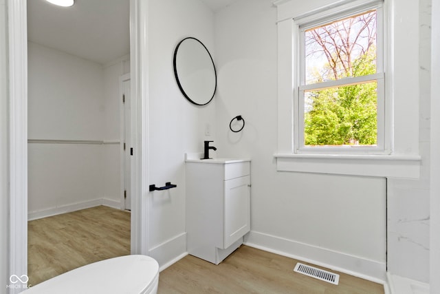 bathroom with visible vents, wood finished floors, and a healthy amount of sunlight