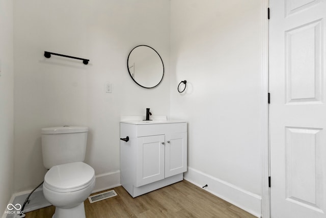 bathroom with visible vents, vanity, wood finished floors, toilet, and baseboards