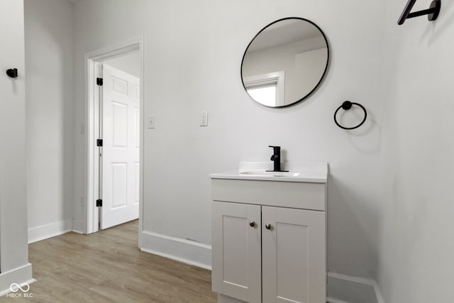 bathroom with baseboards, wood finished floors, and vanity