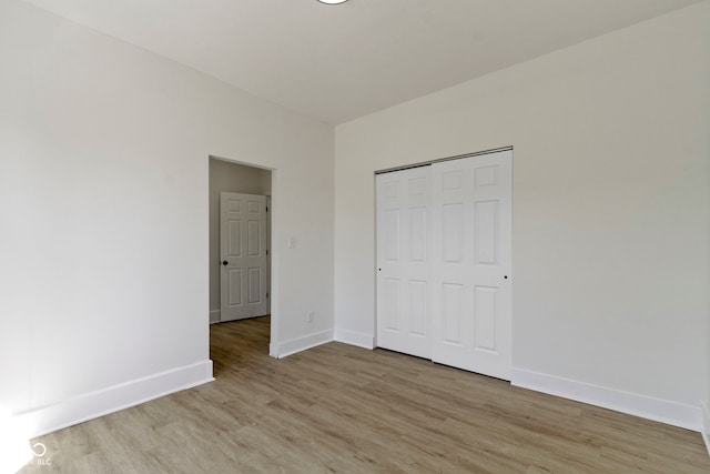 unfurnished bedroom featuring a closet, baseboards, and light wood-type flooring