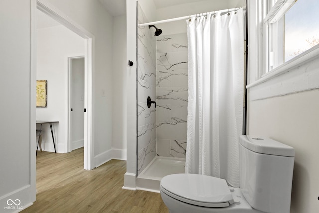 bathroom featuring baseboards, a shower stall, toilet, and wood finished floors