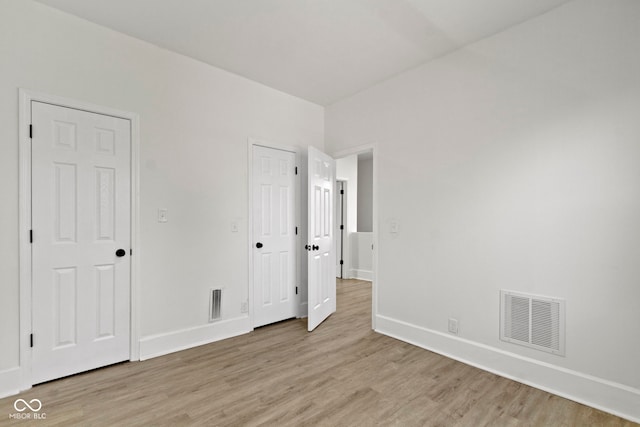unfurnished bedroom with visible vents, light wood-style floors, and baseboards