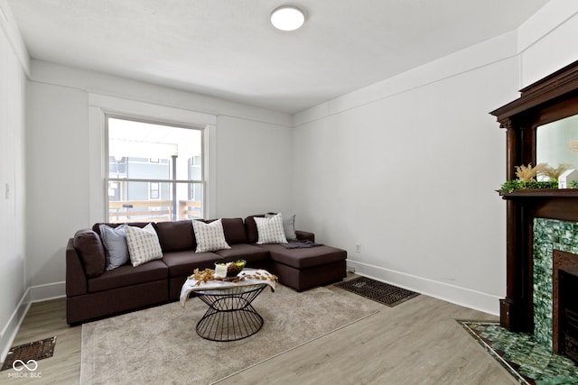 living room featuring baseboards, visible vents, a tiled fireplace, and wood finished floors