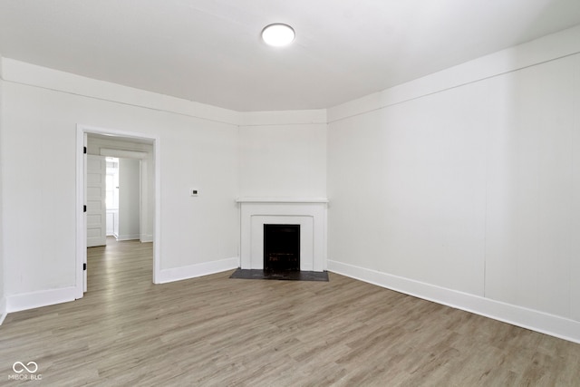 unfurnished living room with light wood-style floors, a fireplace with flush hearth, and baseboards