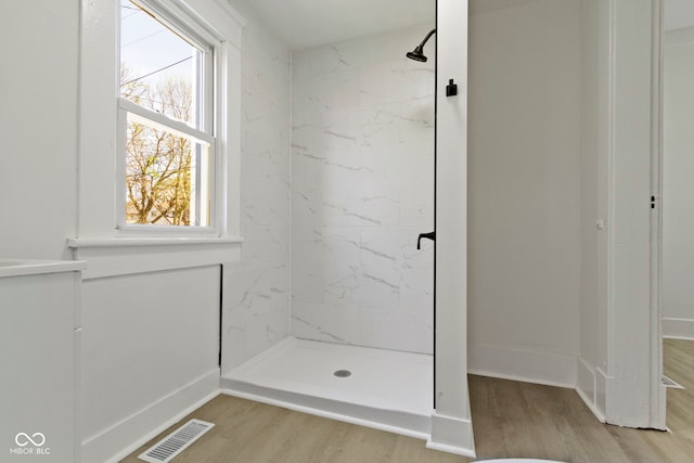 bathroom featuring plenty of natural light, a stall shower, wood finished floors, and visible vents