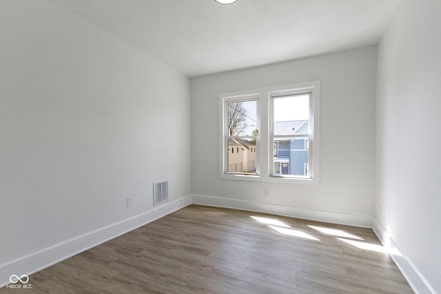 empty room featuring visible vents, baseboards, and wood finished floors