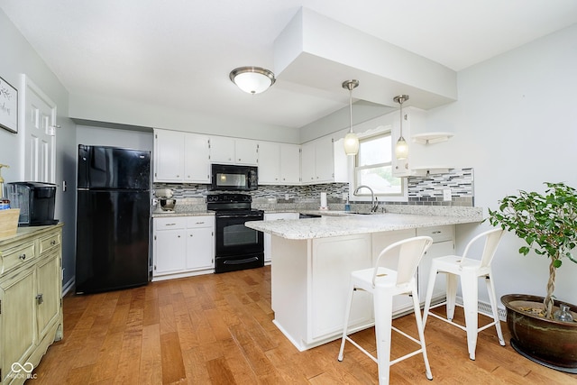 162 Carmelaire Dr, Carmel, IN 46032 - kitchen featuring black appliances, a peninsula, light wood-style flooring, and decorative backsplash