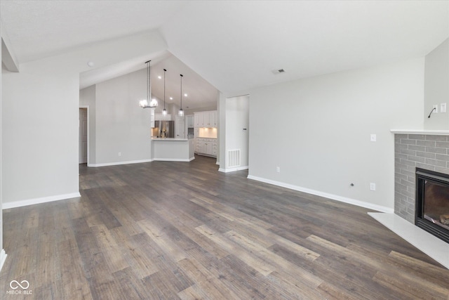 unfurnished living room featuring a brick fireplace, vaulted ceiling, dark wood-style flooring, and baseboards
