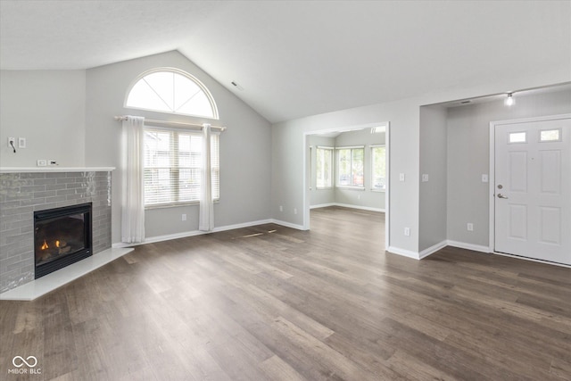 unfurnished living room featuring lofted ceiling, a brick fireplace, dark wood-style flooring, and baseboards