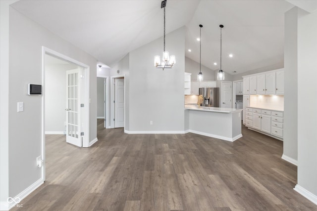 unfurnished living room with dark wood-type flooring, high vaulted ceiling, a chandelier, baseboards, and recessed lighting