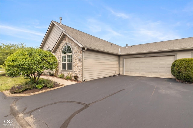 view of front of home featuring asphalt driveway, stone siding, and an attached garage