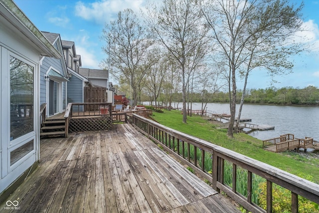 wooden terrace featuring a yard, a water view, and a boat dock