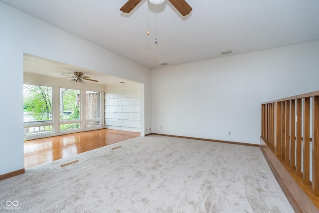 empty room with carpet floors, a ceiling fan, and baseboards