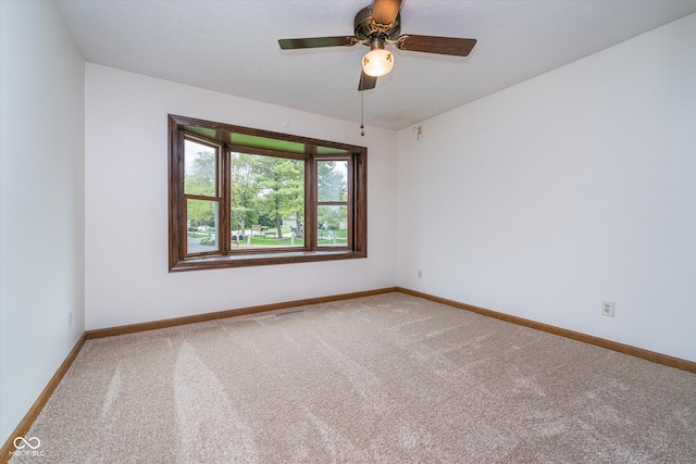 carpeted spare room with baseboards and a ceiling fan