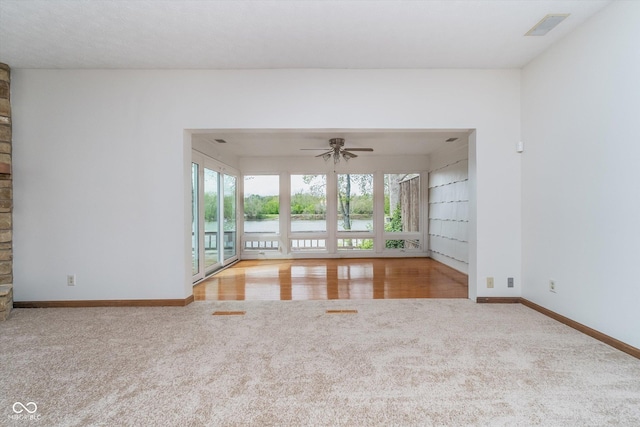 unfurnished living room with a ceiling fan, baseboards, visible vents, and carpet